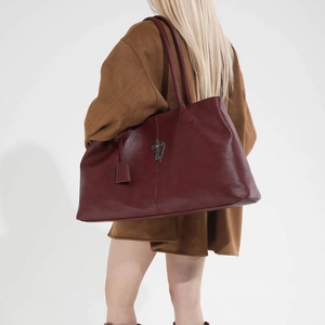 Dettaglio borsa tote in pelle bordeaux con croce in metallo vintage e tracolla lunga