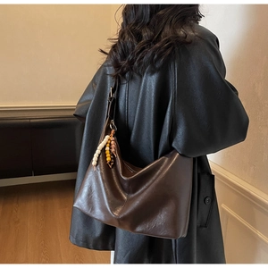 Détail du sac hobo marron foncé avec pendentif bohème en perles de bois colorées