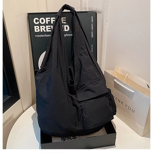 Detail view of large black tote bag with side utility pockets and waterproof nylon texture