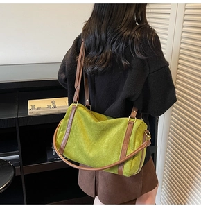 Détail du cabas en daim vert avec lanières en cuir marron et boucles métalliques
