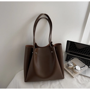 Detail of dark brown leather tote bag with silver metal studs and office accessories