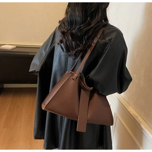 Close-up of brown litchi pattern leather shoulder bag on a model wearing black leather
