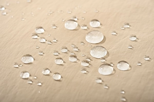 Vue macro d'un tissu beige imperméable avec gouttes d'eau et effet hydrophobe