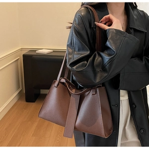 Deep brown litchi pattern leather dumpling bag shown on a model in a minimalist studio