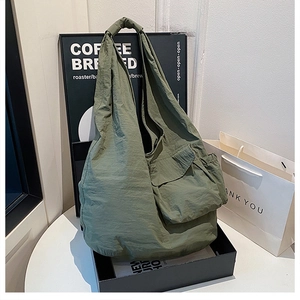 Detail of the army green nylon tote bag featuring a large flap pocket and pleated texture