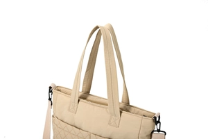 Détail du cabas en nylon matelassé beige avec poignées renforcées et boucles noires