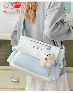 Gros plan sur le sac messager en toile avec icônes d'ours et pendentif peluche