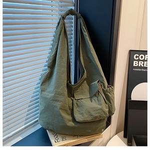 Detailed view of the large olive green nylon tote bag with functional pockets and wide strap