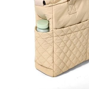 Gros plan de la poche latérale fonctionnelle sur le sac cabas en nylon matelassé beige