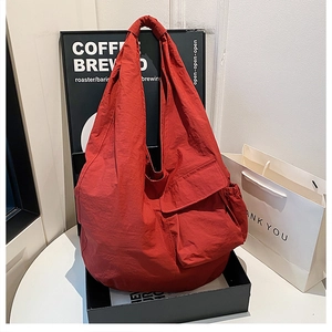 Detail of red nylon tote bag with utility side pocket and textured fabric finish