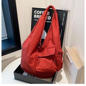 Detail of red nylon shoulder bag featuring multiple pockets and waterproof material