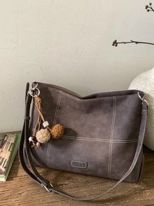 Minimalist large-capacity brown tote bag with contrast stitching and ethnic pendant charm
