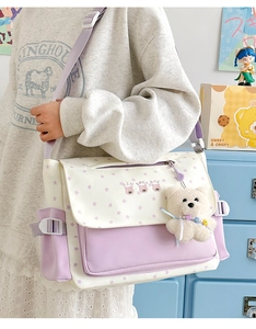 Détail du sac messager en toile à motif d'étoiles avec un pendentif d'ours peluche