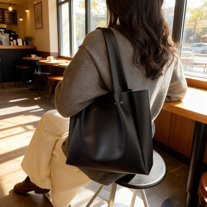 Minimalist black large capacity tote bag for women shown in a cozy cafe setting