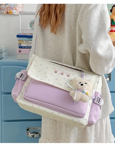 Détail du sac messager en toile à motif étoiles mauves avec un pendentif ours en peluche
