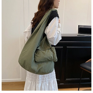 Macro detail of olive green canvas tote bag showing the flap pockets and crossbody strap