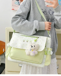 Détail d'un sac bandoulière vert menthe avec motifs d'étoiles et un charmant ours en peluche