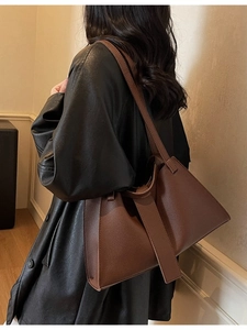 Fashionable dark brown leather dumpling bag worn on shoulder for stylish commuting women