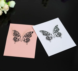 Elegant laser-cut butterfly place cards in pink and white with intricate hollow patterns