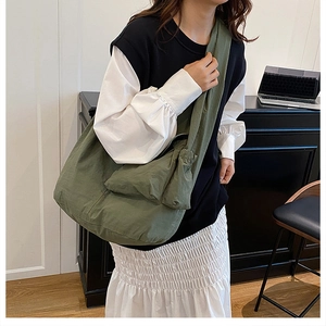 Detail view of the olive green nylon shoulder bag featuring side pocket and textured fabric