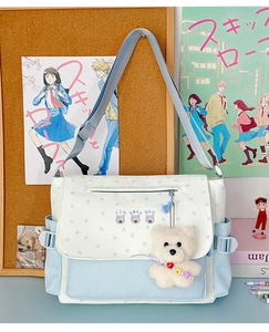Détail de sac bandoulière à motif étoiles avec pendentif ours et contraste bleu et blanc