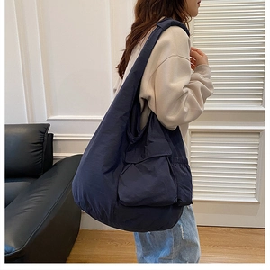 Detail of navy blue large capacity tote bag with front pocket shown on shoulder
