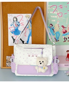 Détail du sac bandoulière en toile à motif d'étoiles avec porte-clés ours sur un bureau