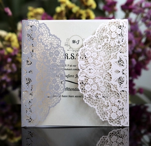 Macro detail of laser-cut lace wedding invitation with pearlized finish and RSVP text