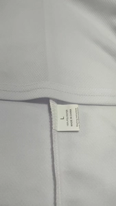 Detalle de la etiqueta de lavado que muestra el tejido 100% poliéster y la talla L