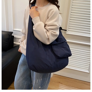 Detail of navy blue hobo bag showing a large side flap pocket and lightweight nylon texture