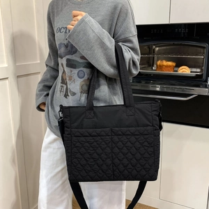 Détail du sac cabas matelassé noir en nylon porté en bandoulière pour le quotidien