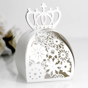 Close-up of laser-cut wedding favor box with crown top and hollow floral dress pattern
