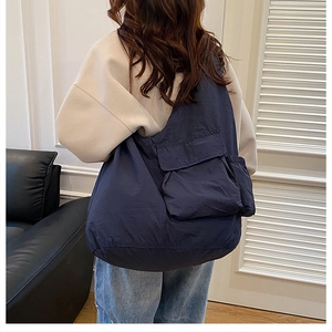 Detail view of navy blue large capacity shoulder bag with flap pocket and drawstring