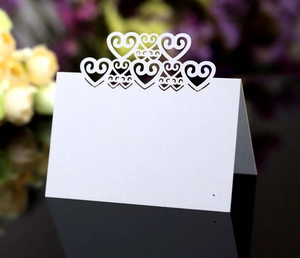 Macro shot of white laser-cut hollow heart table card for wedding seat arrangements