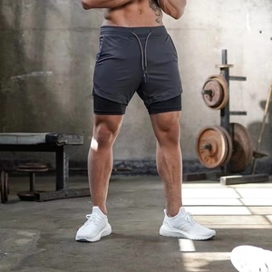 Detail view of men's layered athletic shorts with drawstring in a gym setting