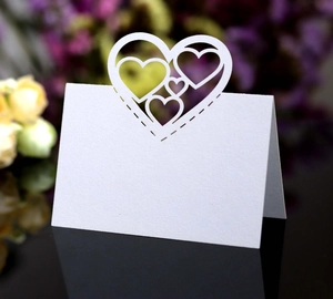 Macro shot of white laser-cut hollow heart table cards for wedding ceremony seating