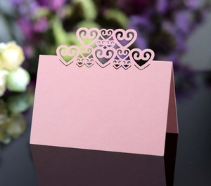 Detailed laser-cut heart design on pale pink wedding place cards with floral decor