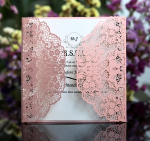 Detail of laser-cut lace wedding invitation in soft pink with RSVP card and floral decor