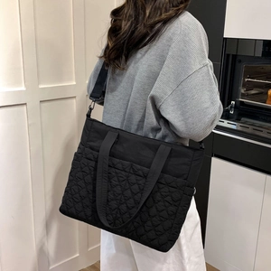 Détail du sac cabas matelassé noir avec bandoulière en nylon et coutures en losange