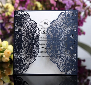 Detailed view of laser-cut lace wedding invitation with dark blue floral hollow pattern