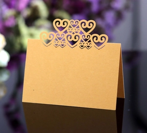 Detail of laser-cut heart hollow design on gold wedding place cards for event tables
