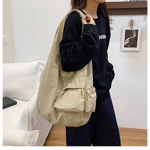 Detail view of khaki shoulder bag featuring large front flap pocket and drawstring side pouch