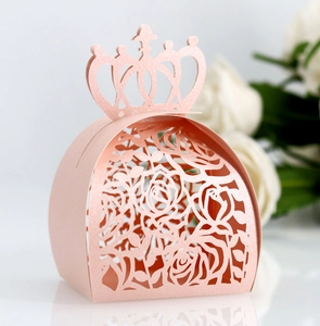 Pink crown hollow laser-cut favor box with elegant rose patterns on a glossy surface