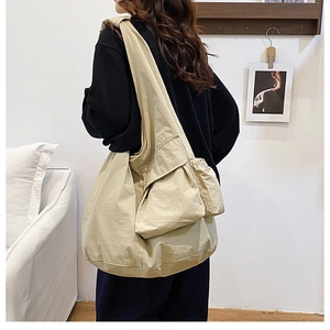 Detail view of khaki nylon tote bag featuring functional side pockets and wide strap design
