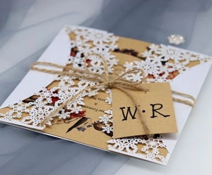 Close-up of laser-cut white snowflake invitation with rustic twine and Kraft paper tag