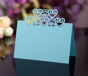 Close-up of light blue laser-cut hollow heart table card on reflective surface