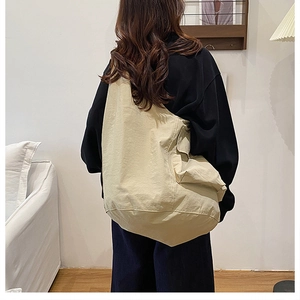 Detail view of large beige canvas tote bag with side flap pocket and adjustable strap