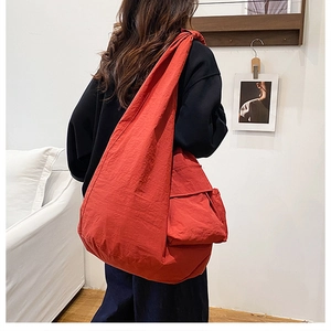 Detail view of large red nylon tote bag with spacious side pockets and wide shoulder strap