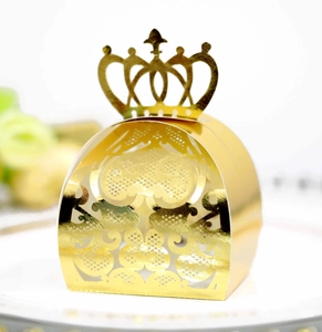 Macro shot of gold wedding favor box featuring laser-cut floral patterns and a crown top