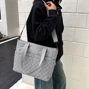 Détail du sac fourre-tout gris matelassé à motif losanges avec bandoulière réglable